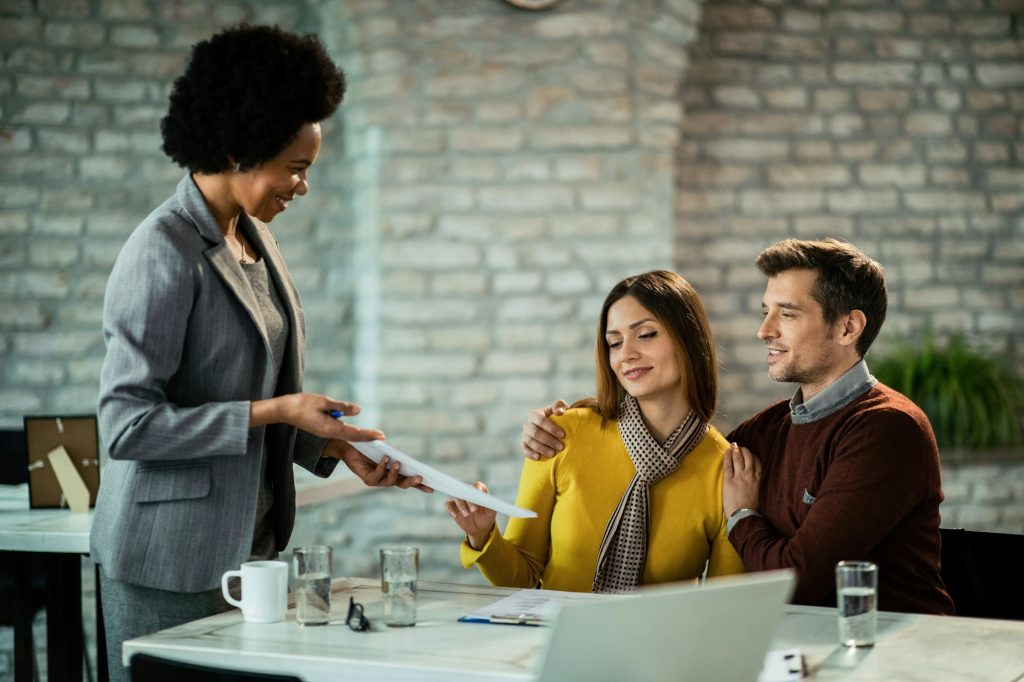 Happy couple having a business meeting with African American bank manager.