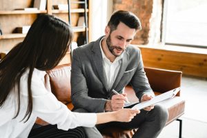 Male and female business colleagues signing legal documents together in modern office.